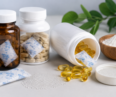 Silica gel sachets and desiccant beads placed alongside nutraceutical supplement bottles, capsules, and powder for moisture protection.